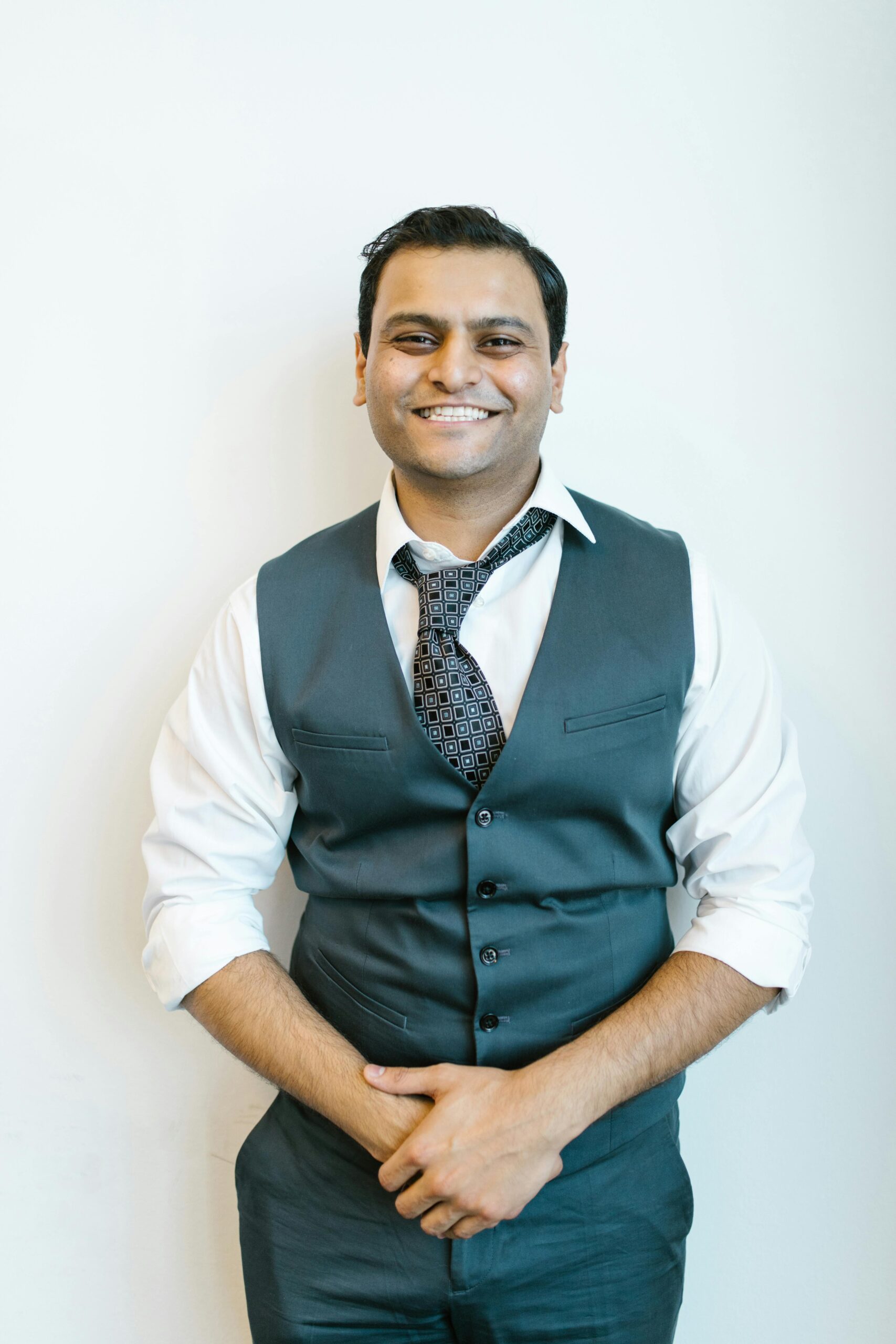 Portrait of a cheerful man in business attire posing confidently indoors.